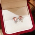 Détail macro de boucles d'oreilles fleurs en argent avec zircon rose dans un écrin rouge - Clou d'oreille en argent - Rose