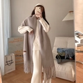 Soft grey cashmere-feel scarf with long tassels shown in a cozy lifestyle setting - Cream Gray