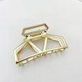 Close-up of golden geometric hollow metal hair claw clip with polished alloy finish - Gold