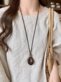 Détail d'un collier vintage avec pendentif goutte en résine et perle verte décorative - Collier Goutte d'eau Café