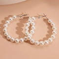 Dettaglio di grandi orecchini a cerchio con perle bianche e perni in argento su fondo beige - Cerchio Grande Con Perle Grandi