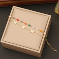 Primer plano de cadena doble dorada con mariposa blanca y cuentas de colores sobre caja - Estilo 3 mariposas nº 4