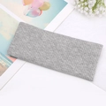 Close-up of a light grey knitted headband with ribbed texture and twisted knot detail - Gray