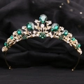 Detail of a baroque crown with emerald green gems and rhinestones on a black background - KC Gold White Diamond + Green Diamond