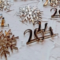 Close-up of gold mirror acrylic snowflake and 2024 number laser cut cake toppers - 2024 - Gold