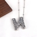 Macro shot of silver letter N pendant necklace with textured metal surface and bead chain - Letter N