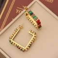 Detail of gold C-shaped earrings with colorful rectangular zircons on jewelry display - 4# Square
