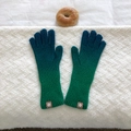 Detail of blue and green gradient knit gloves with logo patch on a textured background - Dark Green