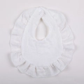 Detailed view of white double-layer cotton gauze baby bib with ruffled edge and snap button - White