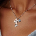 Collana con ciondolo a fiore d'argento e gemma blu indossata sul collo di una donna - Marzo