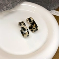 Close-up of leopard print resin C-shaped hoop earrings on a white ceramic tray - 31# Steel Pin - Grey Leopard (Acrylic C-Shape)