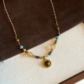 Macro detail of bronze pendant with dark brown tiger eye gemstone on woven beaded chain - Gold Round Pendant Style