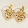 Macro detail van vergulde hartvormige oorbellen met sprankelende baguette-cut zirkonia's - Goud Hart