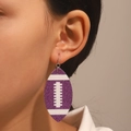 Détail macro de boucles d'oreilles football à paillettes violettes portées par un mannequin - PU Blanc K Violet (4055)