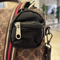 Detail of a black nylon mini coin purse with silver zipper attached to a striped strap - Black