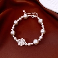 Macro detail of French style pearl bracelet with zircon flower pendant on brown silk fabric - Hollow Flower Pendant Style / Silver-Pearl White