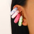 Macro shot of colorful splattered capsule ear cuffs in blue, pink, and green resin - Multicolor Variety