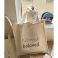Borsa tote in tela crema con ricamo marrone su un tavolo in legno soleggiato - Ricamo Sfumato Marrone