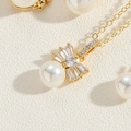Dettaglio macro della collana a fiocco dorato con perla bianca e pietre di zircone - Collana Di Perle Con Fiocco (Oro)