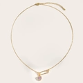 Detailed close-up of a gold safety pin necklace with a sparkling pink heart pendant - Gold