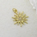 Detailed view of a gold sun pendant with sparkling cubic zirconia on a beige stone surface - Gold Zircon Sun