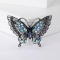 Dettaglio della spilla a farfalla retrò in argento con strass colorati e ali traforate fini - Blu