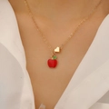 Dettaglio della collana con ciondolo a mela rossa e cuore dorato su camicia bianca - Collana Stile Mela (0059)
