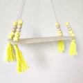 Detail of wooden wall shelf featuring yellow geometric beads and soft yarn tassels - Yellow