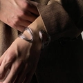 Detalle del brazalete abierto retorcido de varias capas plateado con una chaqueta marrón - Plateado