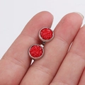 Macro detail of 8mm red stardust earrings held in hand to show size and texture - Red (29)