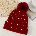 Detail of red ribbed knit beanie featuring pearls, beads, and a large fluffy pom-pom - One Size / Wine Red