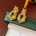Macro shot of gold teardrop earrings with yellow gemstones and diamond accents - Ear Clip - Gold