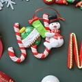 Weihnachts-JOY-Anhänger mit Zuckerstangen, Schneemann und Geschenk auf grünem Grund - Schneemann-Buchstabenschild (JOY) 12*9CM