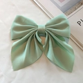 Detailed close-up of mint green silk satin bow hair clip on a minimalist background - Green