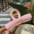 Nahaufnahme einer rosa Harz-Haarklammer mit Goldschleife, gehalten im Freien am Licht - Groß (10cm) / Aprikosenrosa