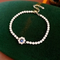 Détail macro d'un bracelet de tennis fleur en argent avec pierres bleues sur velours - Fleur Bleue / Argent-Bleu