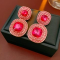 Makro-Detail von Vintage-Gold-Ohrringen mit roten Steinen und rosa Kristallen - Silberner Ohrring-Stift - Rot