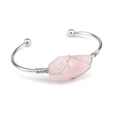 Detail view of pink raw crystal wrapped in silver copper wire on an open cuff bracelet - Rose Quartz