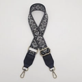 Detail of adjustable 38mm embroidered canvas bag strap with retro jacquard floral patterns - Antique Brass Hook / Black Base Grey with Black Leather