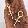 Close-up of gold-plated cross earrings with zircon pavé hanging on a rustic wood branch - 14K Gold Pave Huggie Cross