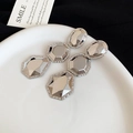 Gros plan de boucles d'oreilles géométriques argentées sur un plateau en céramique blanc - Boucles d'oreilles clous / Argent