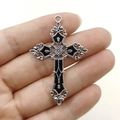 Ciondolo a croce argento vintage con motivi floreali neri tenuto tra le dita - Croce Nera Decorata Gotica (Piatta)