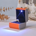 Macro di una scatola per anelli ottagonale con luce LED che illumina il gioiello - Scatola per anelli / Arancione