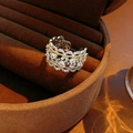 Makroaufnahme von silbernem und goldenem Spitzenring mit Zirkon-Inlay auf Samt - Silber-Gold Bi-Color Hohl-Stil