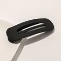 Macro shot of minimalist matte black hair clip with geometric cutout on white surface - Matte Hair Clip Large - Black