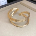 Dettaglio di un bracciale dorato multistrato intrecciato su vassoio espositivo - Oro