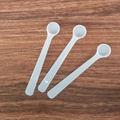 Three white long-handled plastic measuring spoons on dark wood background - 0.5ml Long Handle (9.5*1.6*1cm) / White