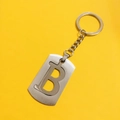 Top view of hollow letter B stainless steel keychain with ring on yellow background - Letter B