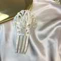 Close-up of white acetate hair comb with shell luster on elegant silk background - Milky White