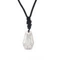 Dettaglio di un ciondolo esagonale in marmo bianco con cordino nero intrecciato a mano - Howlite